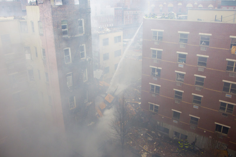 New York City firefighters hose down the rubble from a building that collapsed on Park Ave. and 116th Street in New York, March 12, 2014. (Gordon Donovan)
