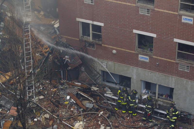 New York City firefighters hose down the rubble from a building that collapsed on Park Ave. and 116th Street in New York, March 12, 2014. (Gordon Donovan)