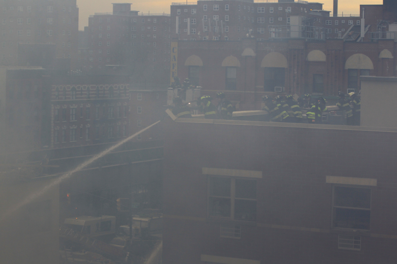 Through the smoke across the courtyard, New York City firefighters hose down rubble from rooftops above after two buildings collapsed on Park Ave. and 116th Street in New York City, March 12, 2014. (Gordon Donovan/Yahoo News)