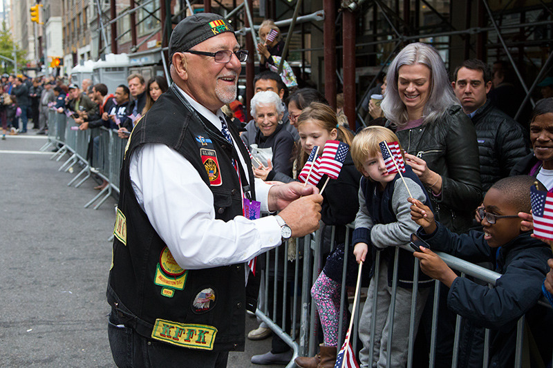Joe T. from Brooklyn, a member of the Nam Knights, hands out flags to spectators during the Veterans Day parade on Fifth Avenue in New York on Nov. 11, 2014. (Gordon Donovan)
