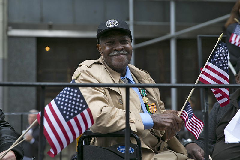 A veteran is all smiles as waves a flag on board a float up Fifth Avenue during the Veterans Day parade in New York City. (Gordon Donovan)