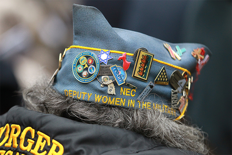 Highly decorated: the hat of a veteran is dressed up with pins as she listens to a speech before the Veterans Day parade. (Gordon Donovan)