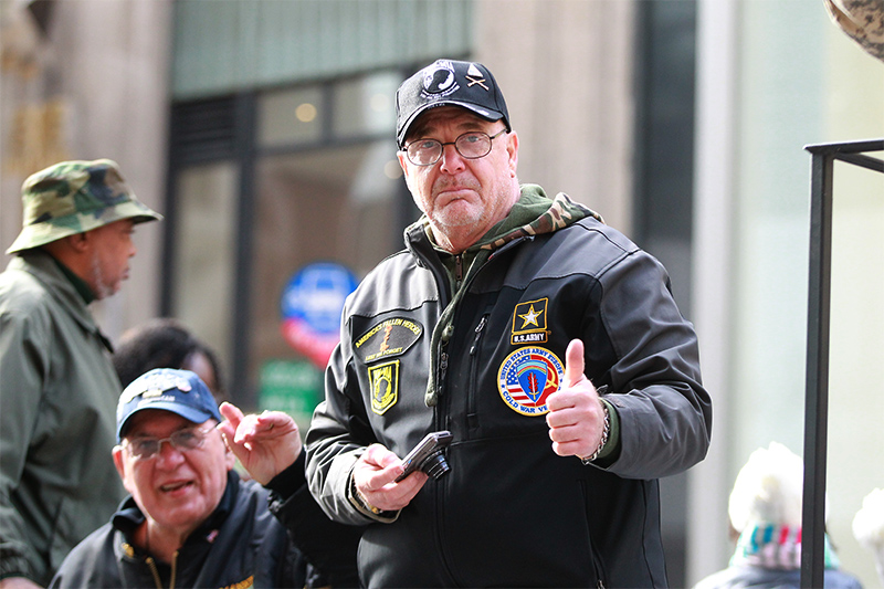 A veteran gives a thumbs up to spectators on board a float during the Veterans Day parade. (Gordon Donovan)