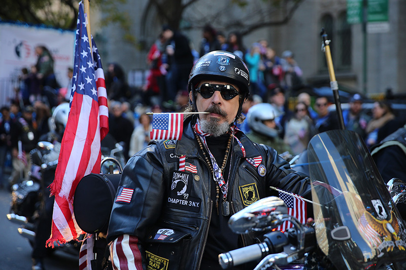 A veterans carries a flag in his teeth while riding his motorcycle during the Veterans Day parade on Fifth Avenue in New York on Nov. 11, 2016. (Gordon Donovan)