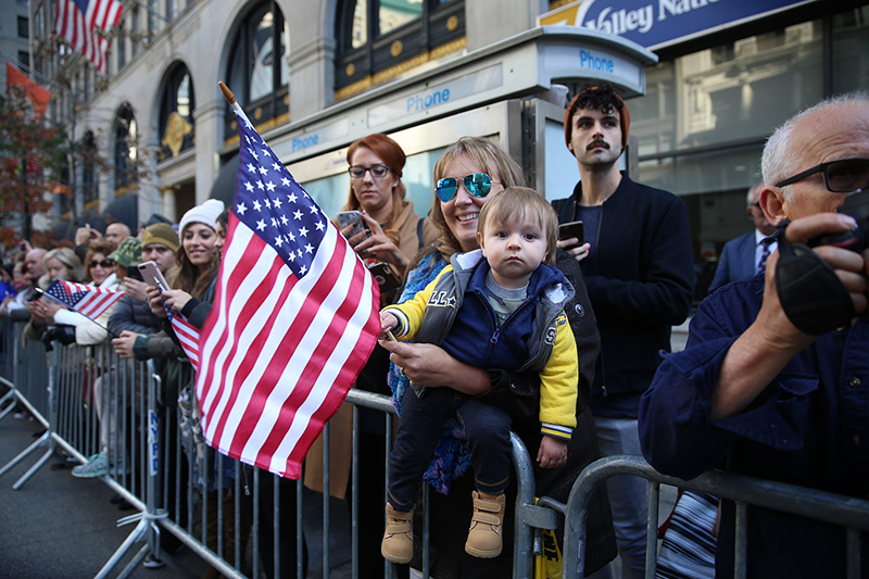 A woman and baby wave a flag as vets march during the Veterans Day parade on Fifth Avenue in New York on Nov. 11, 2016. (Gordon Donovan)
