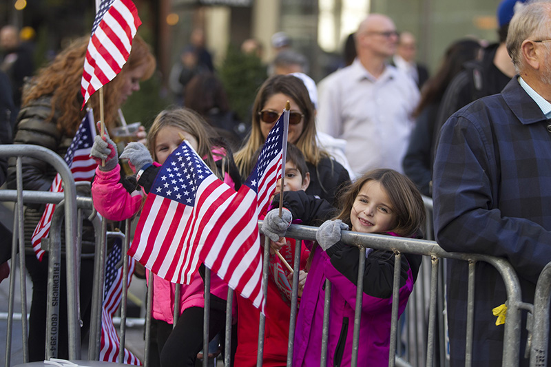 Young spectators wave flags as members of the armed forces march during the Veterans Day parade on Fifth Avenue in New York on Nov. 11, 2016. (Gordon Donovan)