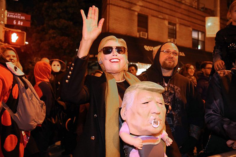A woman wears a Hollary Clinton mask while holding a baby in a Trump mask in the 43rd annual Village Halloween Parade in New York City on Monday, Oct. 31, 2016. (Gordon Donovan/Yahoo News)