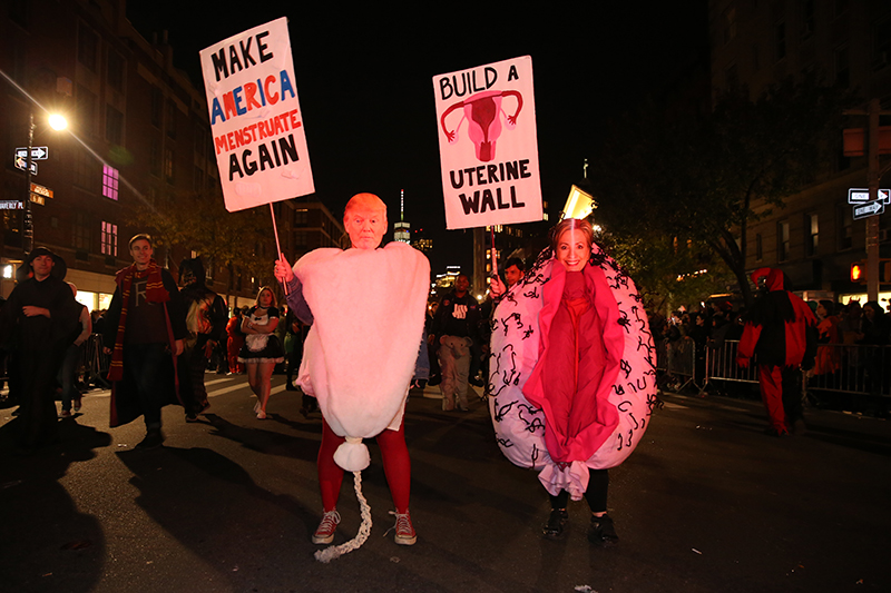 People wearing Hillary Clinton and Donald Trump masks, dressed as female hold up signs during the 43rd annual Village Halloween Parade in New York City on Oct. 31, 2016. (Gordon Donovan/Yahoo News)