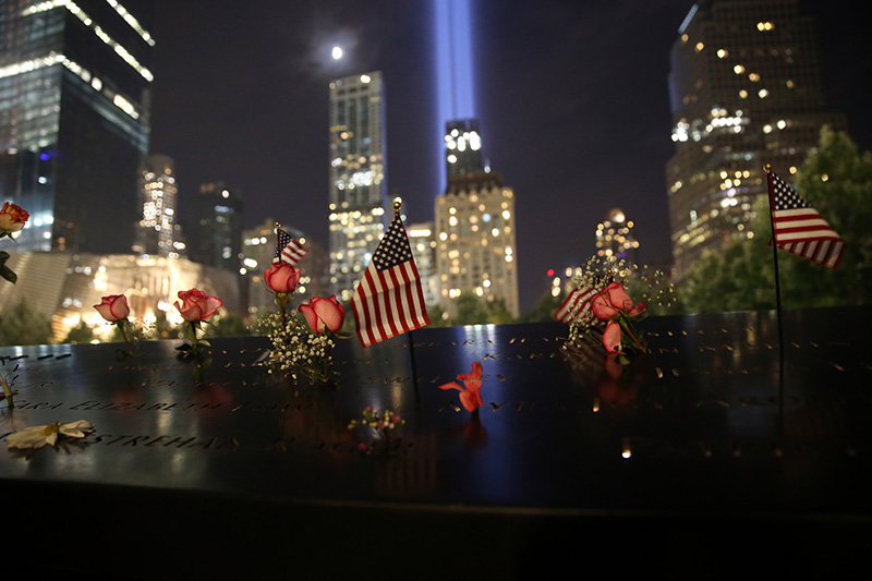 Flowers and flags lay on top of one of the panels at the North Pool of National September 11 Memorial & Museum as the Tribute in Light rises above the New York skyline on Sept. 10, 2016. (Gordon Donovan/Yahoo News)