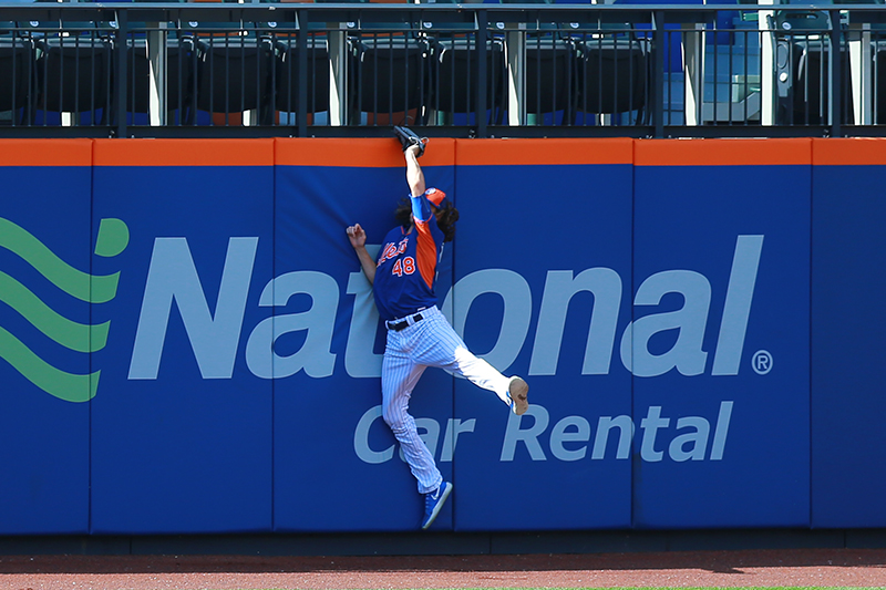 New York Mets pitcher Jacob deGrom (48) leaps up and crashes into outfield wall making a catch during batting practice before the baseball game against the Miami Marlins at Citi Field in New York, Tuesday, July 5, 2016. (Gordon Donovan)