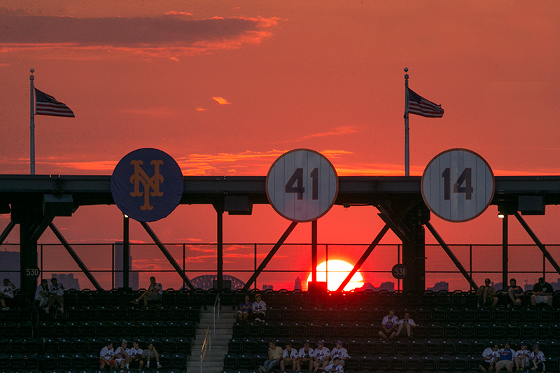 The sun begins to set just behind the retired numbers on a beautiful night for baseball as the Colorado Rockies and New York Mets play at Citi Field in New York, Friday, July 29, 2016. (Gordon Donovan)