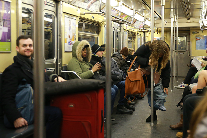 A participant of the No Pants Subway Ride remove their pants as onlookers watch on the subway in New York City, Sunday, Jan. 8, 2017. (Gordon Donovan/Yahoo News)