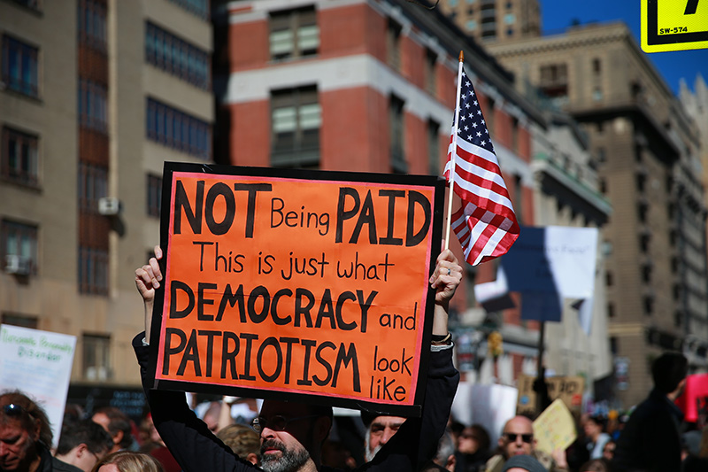 A demonstrator holds up an orange sign and U.S. flag during the “Not My President’s Day” rally on Central Park West in New York City on Feb. 20, 2017. (Gordon Donovan/Yahoo News)