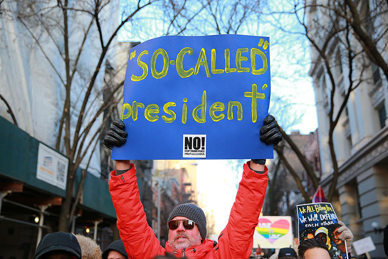 A man holds up a sign high during a rally in front of the Stonewall Inn in solidarity with immigrants, asylum seekers, refugees, and the LGBT community, Feb. 4, 2017 in New York. (Photo: Gordon Donovan/Yahoo News)