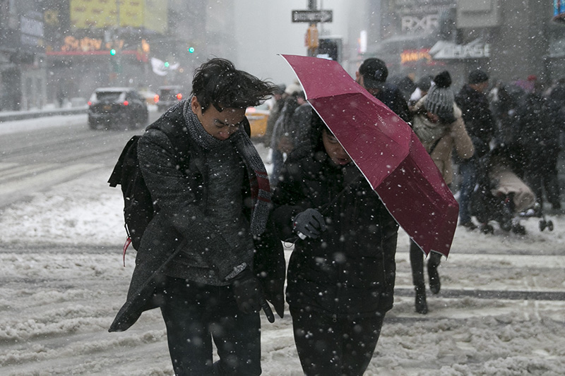 People use their umbrella as a shield to brace the high winds and snow as they cross the street in Times Square in New York City on Feb. 9, 2017. (Gordon Donovan/Yahoo News)