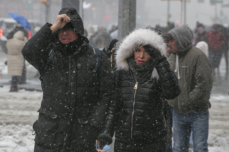 People hold their hoods as fight off high winds and snow as they cross the street in Times Square in New York City on Feb. 9, 2017. (Gordon Donovan/Yahoo News)