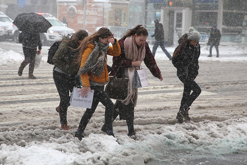 Several women forgot their hats as they shield themselves against high winds and snow as they cross the street in Times Square in New York City on Feb. 9, 2017. (Gordon Donovan/Yahoo News)