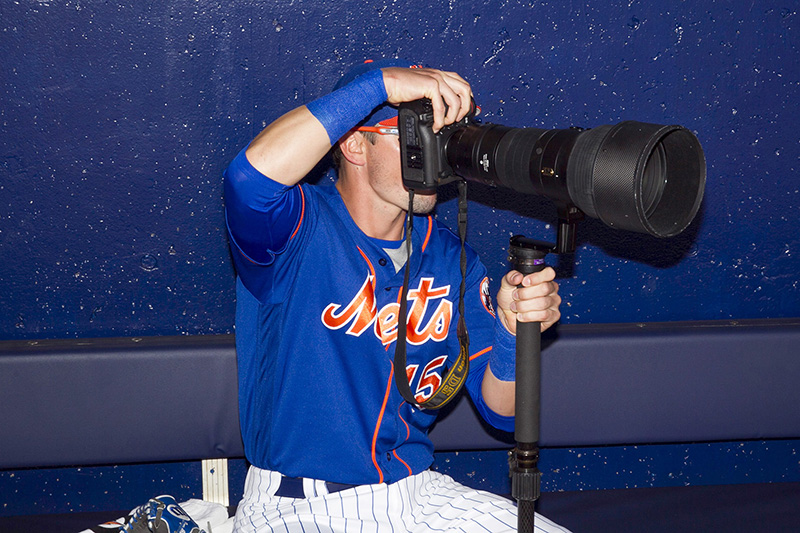 New York Mets infielder Matt Reynolds takes aim with Mets team photographer Marc Levine camera that was left in the dugout before the baseball game against the Detroit Tigers at First Data Field in Port St. Lucie, Fl., Sunday, Feb. 26, 2017. (Gordon Donovan/Yahoo Sports)